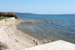 una orilla rocosa de un gran cuerpo de agua en Apartments by the sea Sukosan, Zadar - 12313, en Sukošan
