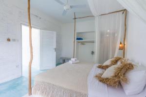 a white bedroom with a bed with a wooden canopy at Guru Canggu in Canggu