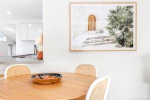 a kitchen with a wooden table with chairs and a picture on the wall at Styled 3 BR Tropical Family Home w Pool at Coolum in Coolum Beach