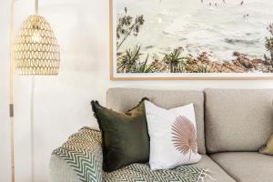 a living room with a couch with pillows and a painting at Styled 3 BR Tropical Family Home w Pool at Coolum in Coolum Beach