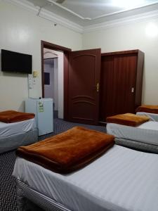 a hotel room with three beds and a tv at امجاد منى in Makkah