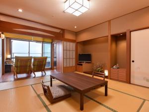 sala de estar con mesa de madera y sillas en Hotel Sanrakuso, en Shirahama