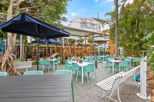 restauracja ze stołami, krzesłami i parasolem w obiekcie The Colmslie Hotel w mieście Brisbane