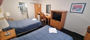 a hotel room with two beds and a desk and a television at Queensport Tavern And Motel in Brisbane
