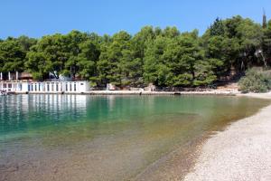 a beach with a white building in the water at Apartments and rooms with parking space Stari Grad, Hvar - 14888 in Stari Grad