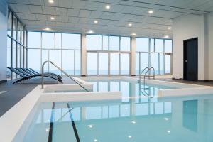 een zwembad met 2 stoelen in een kamer met ramen bij Riotel Matane in Matane