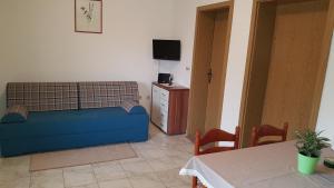 a living room with a blue couch and a tv at Apartments by the sea Slatine, Ciovo - 4844 in Slatine