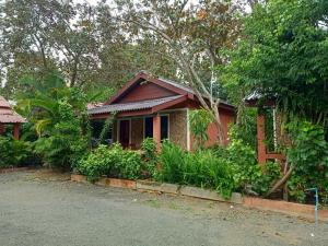 a small red house with plants in front of it at Pina House in Kep
