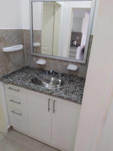 een badkamerbar met een wastafel en een spiegel bij Antonia in Villa Elisa
