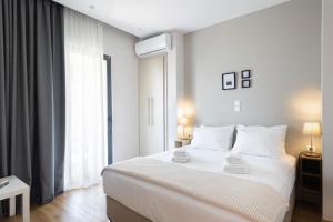 a white bedroom with a large bed and a window at Mood Athens Luxury Apartments and Suites in Athens