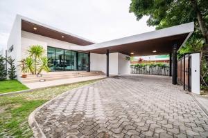 a house with a stone driveway in front of it at Mövenpick Pool Villa4BR-PrivatePool(SHA CERTIFIED) in Na Jomtien