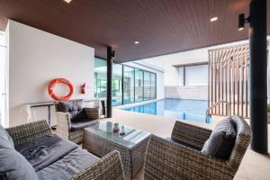un soggiorno con divano, sedie e piscina di Mövenpick Pool Villa4BR-PrivatePool(SHA CERTIFIED) a Na Jomtien