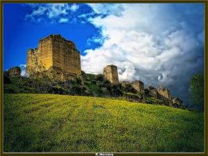 un castello in cima a una verde collina di Hostal Restaurante El Cruce ad Ardales