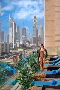a woman walking on the rooftop of a building with a city at Fairmont Dubai in Dubai