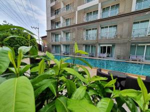 a hotel with a swimming pool in front of a building at Retreat Resort Pattaya in Nong Prue