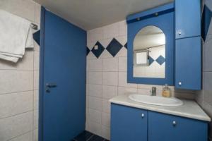 La salle de bains bleue est pourvue d'un lavabo et d'un miroir. dans l'établissement House just on the beach -included 2 canoe, 2 bicycles, à Ravdhoúkha