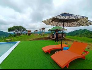 a pool with chairs and an umbrella next to a swimming pool at Captain’s Villa and Campsite in Cebu City