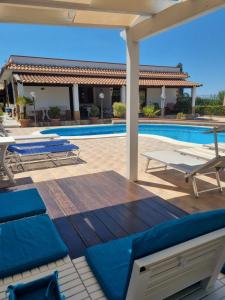 a patio with blue lounge chairs and a swimming pool at Villa Sunshine in Balestrate