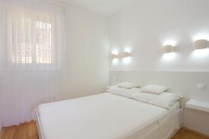 Un dormitorio blanco con una cama blanca y una ventana en Apartments by the sea Rastici, Ciovo - 4818 en Trogir