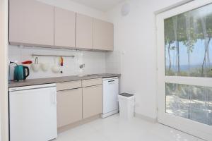 cocina con armarios blancos y ventana grande en Apartments by the sea Rastici, Ciovo - 4818 en Trogir