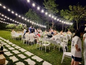 un grupo de personas sentadas en mesas bajo las luces en VEDANA VILLAS RESORT NINH BÌNH, en Phủ Nho Quan