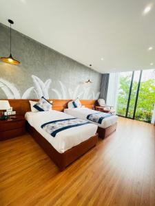 two beds in a large room with wood floors and windows at VEDANA VILLAS RESORT NINH BÌNH in Phủ Nho Quan