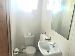a white bathroom with a toilet and a sink at Bay View Apartment 4 - Canouan Island in Canouan