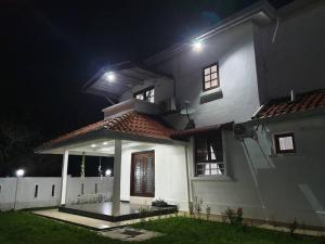Nilai Spring Villas في نيلاي: منزل أبيض مع شرفة في الليل