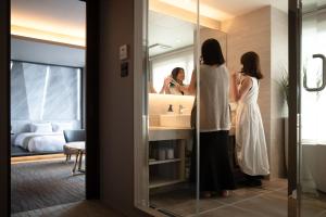 una donna in piedi di fronte a uno specchio del bagno di FAV HOTEL HAKODATE a Hakodate
