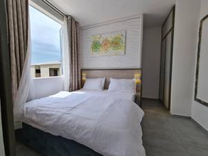 un letto in una camera con una grande finestra di Dolce Vita Palacio a Douala