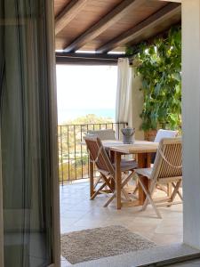 patio con mesa y sillas en el balcón en The refuge on the sea..., en Tertenìa