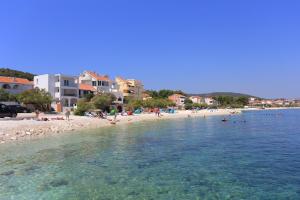 a beach with a bunch of people in the water at Seaside family friendly house with a swimming pool Slatine, Ciovo - 17231 in Slatine