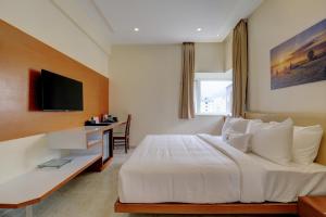 a bedroom with a large white bed and a desk at Tattwa Grand in Yelahanka