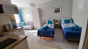コウォブジェクにあるBela - pokoje z aneksami i apartamentyのリビングルーム(ベッド2台付)、キッチンが備わります。