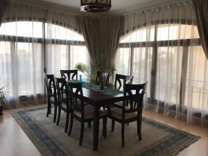 a dining room with a table and chairs and windows at Dreamland upper villa in ‘Ezbet `Abd el-Ḥamîd