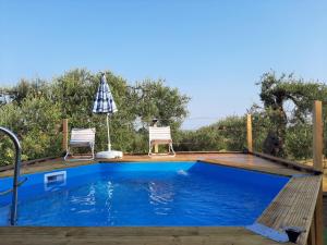 a swimming pool with two chairs and an umbrella at Casa Rustica Lentini in Lascari