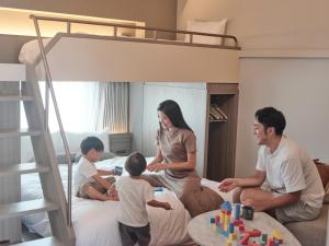 a family sitting in a bedroom with a bunk bed at FAV HOTEL HIROSHIMA STADIUM in Hiroshima