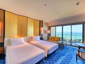 a hotel room with two beds and a balcony at Ryukyu Hotel & Resort Nashiro Beach in Itoman