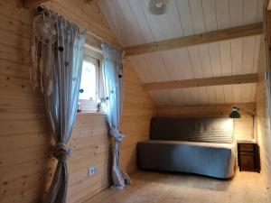 a bedroom in a log cabin with a bed and a window at Na Miedzy in Dźwierzuty