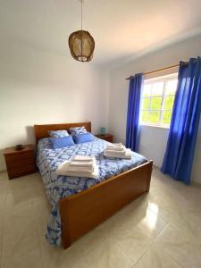 een slaapkamer met een bed met blauwe lakens en blauwe gordijnen bij Moradia penina v3 in Portimão
