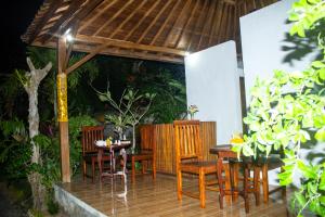 um pátio com uma mesa e cadeiras e um guarda-sol de madeira em Kurnia Guest House & Spa em Nusa Penida