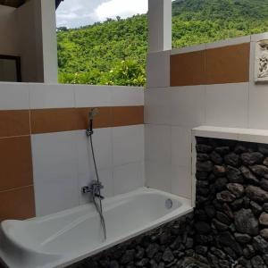 a bathroom with a bath tub with a window at Meditasi Bungalows & Villas in Amed