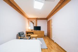 a bedroom with a bed and a desk and a tv at Jeju Miju Hotel in Jeju