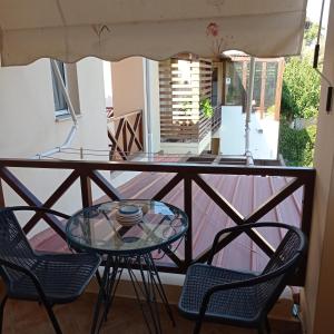 balcón con mesa de cristal y sillas en Oceanides Apartments, en Kourouta