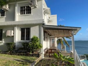 une maison blanche avec une terrasse à côté de l'océan dans l'établissement BEACH VILLA ROCCA, à Grand Gaube