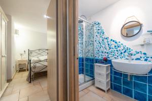 a blue tiled bathroom with a sink and a shower at Casa Vacanza Il Bouganville in Villasimius