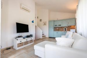 a living room with a white couch and a flat screen tv at Casa Vacanza Il Bouganville in Villasimius