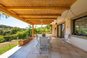 a patio with a table and chairs under a wooden pergola at Casa Vacanza Il Bouganville in Villasimius