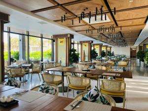 a restaurant with wooden tables and chairs and windows at Mystery Villas & Spa Cam Ranh in Cam Lâm