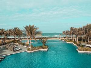 una piscina en un complejo con palmeras y una playa en Mystery Villas & Spa Cam Ranh, en Cam Lâm